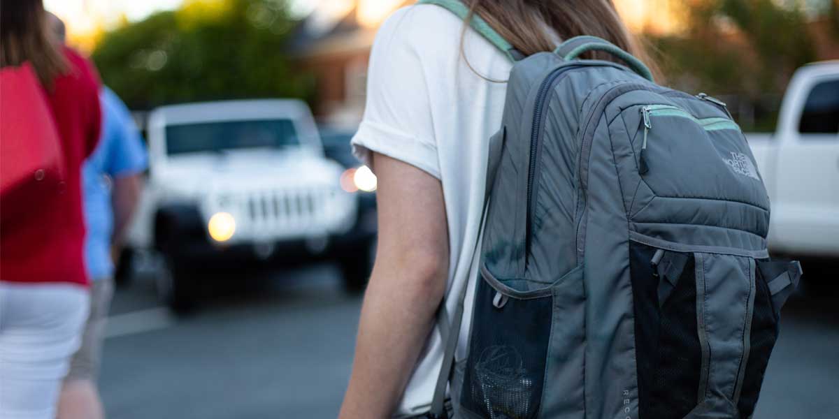 Girl walking with a grey North Face backpack